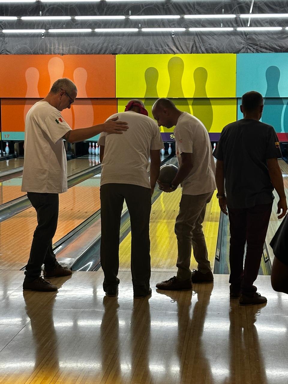 Equipe se apoiando durante partida de boliche em encontro de integração